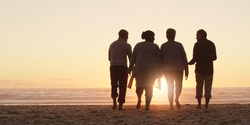 Full length shot of a group of friends enjoying a day out and walking along the beach together